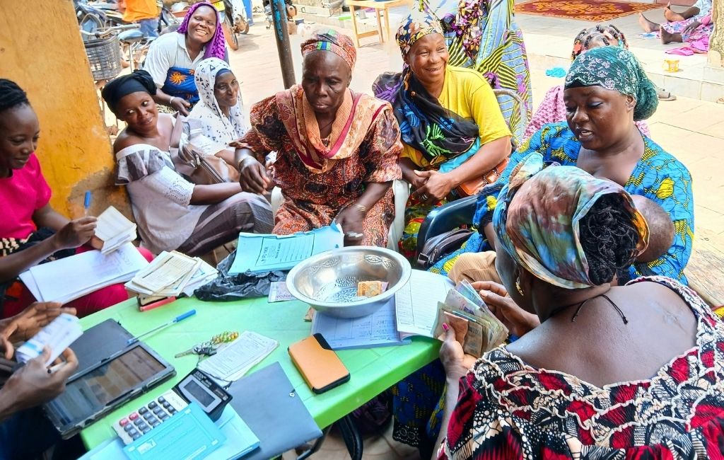plusieurs femmes burkinabè sont assises autour d'une table, prêtes à déposer leur épargne