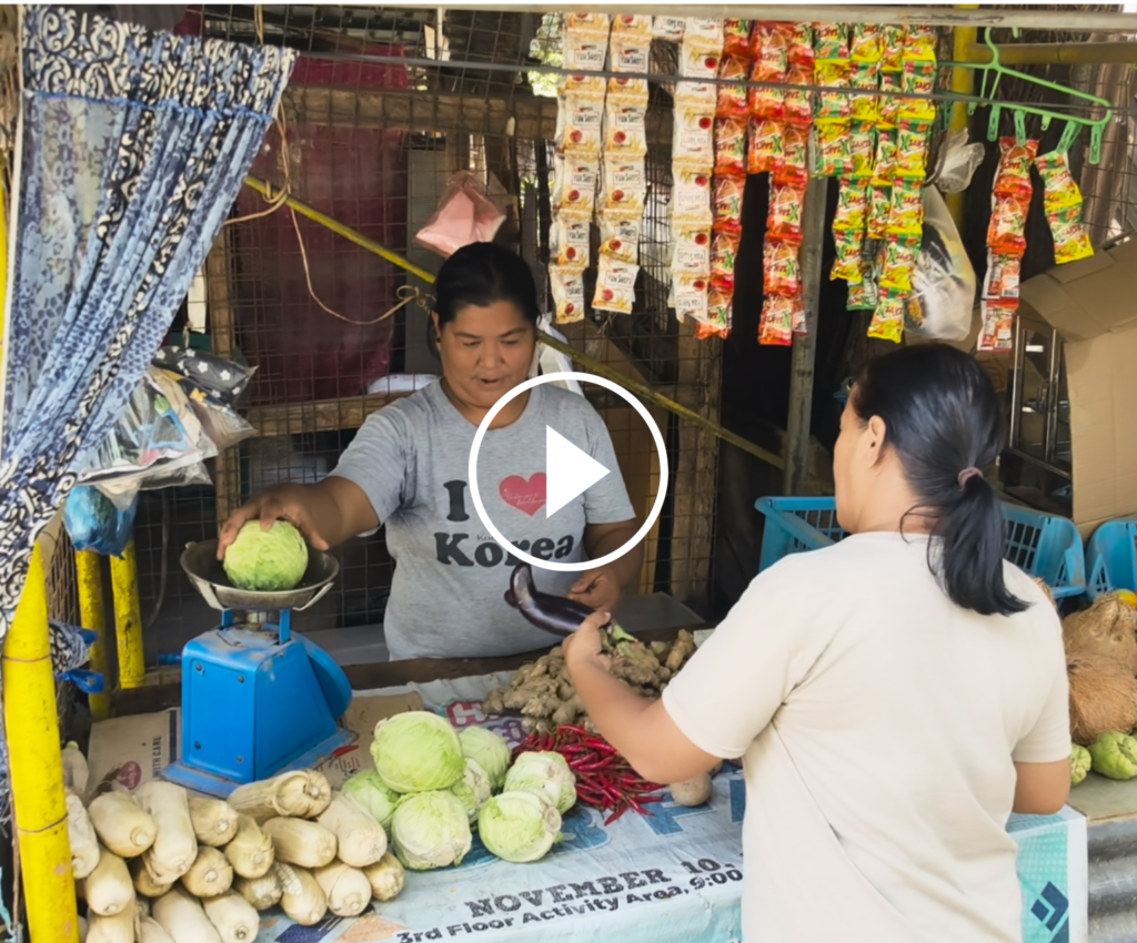 Une commerçante aux Philippines sert une cliente devant son étal de légumes